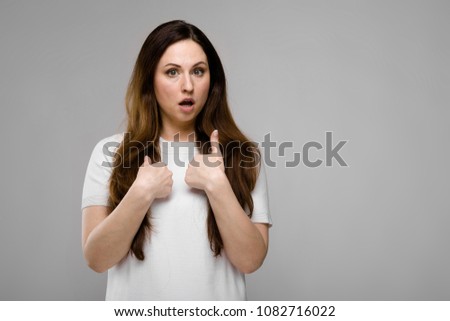 Portrait of emotional puzzled asking plus size model standing in studio looking in camera showing on herself