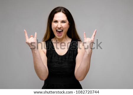 Emotional pretty confident funny plus size model standing in studio fooling on gray background