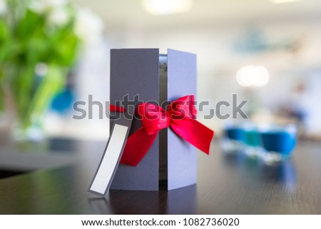 Gift card with red ribbon on the table