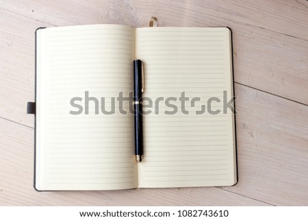 Day planing concept, simple composition. Open paper notebook with lines on pages and ball pen on white wooden background. Peaceful workplace