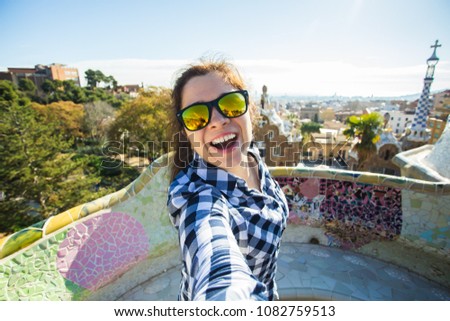 Young happy woman making selfie portrait with smartphone in Park Guell, Barcelona, Spain. Beautiful girl looking at camera taking photo with smart phone smiling