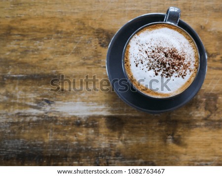 Cup of cappucino coffee on a wood table background. Top view with copy space