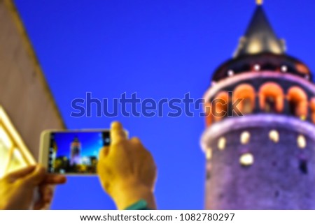 Blurry or de-focused female tourist hands taking photo of Galata Tower in Istanbul Turkey with a smart phone, phone photography