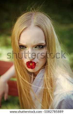 Beauty woman with red flower in mouth. Beauty model with long blond hair, hairstyle.