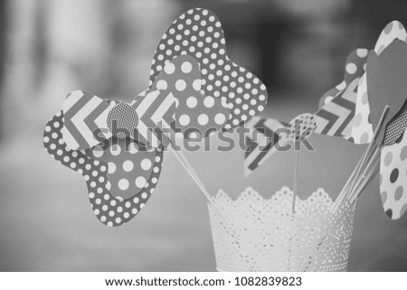 Closeup of few colorful beautiful cardboard handmade bow-ties spotted with stripes blue white and red colors on strokes standing in paper glass on blur background, horizontal picture