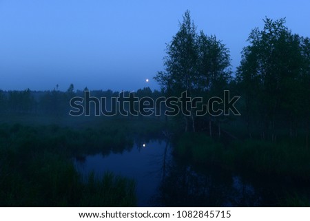 moon in the clear blue night sky over the forest moonlight in the water reflection in the forest river