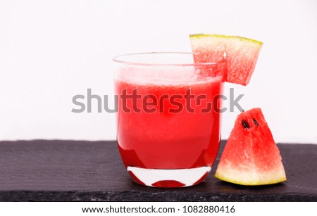 Watermelon juice with slice of watermelon on and beside the glass