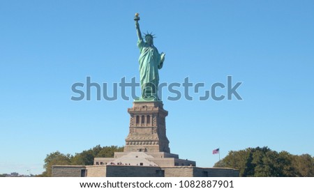 CLOSE UP: Iconic Lady Liberty - the Statue of Liberty National Monument on Liberty Island in New York Harbor, NYC. Crowd of tourists taking photos and gathering around magnificent copper sculpture