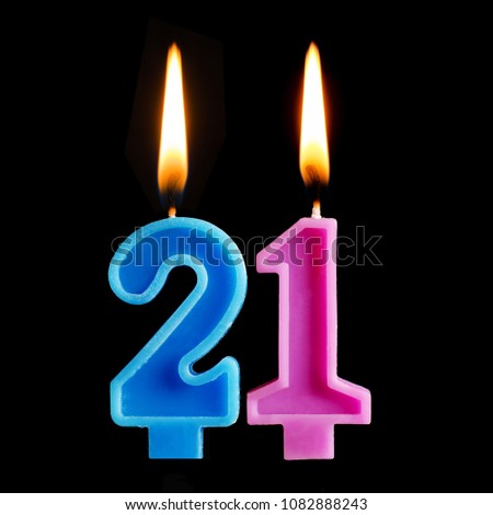 Burning birthday candles in the form of 21 twenty one for cake isolated on black background. The concept of celebrating a birthday, anniversary, important date, holiday