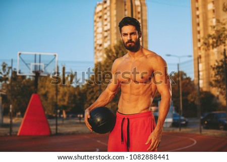 Shirtless handsome man playing basketball