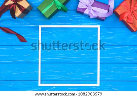 top view of gift boxes and blank frame on blue table
