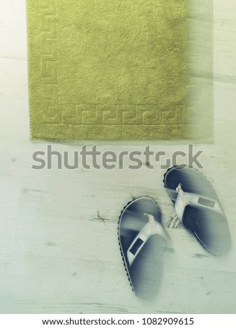 Movement blur picture of sandals and towel signal of summer. Blue sandals and green towel on white wooden floor indicate summer mood. Space for text