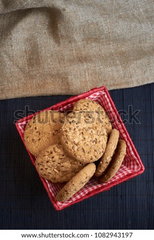 homemade oat cookies with sunflower seeds in and rear red checkered basket on wooden table