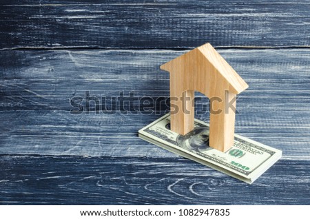 A wooden house stands on a stack of dolor banknotes. The concept of buying and selling immovability, rent of apartments. Credit and mortgage, affordable housing. Utilities payments