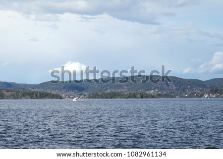 View of fjord and lonely yacht far away in Holmestrand from top of rock near water, Norway.