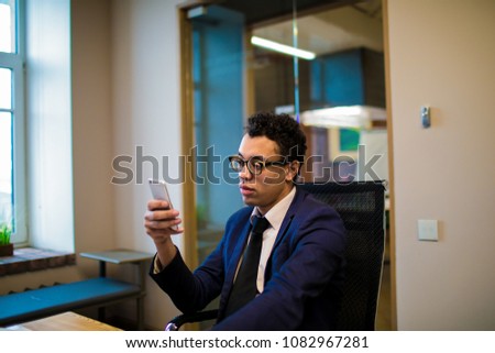 Man professional financier reading text message on portable mobile phone, sitting in office successful company. Male confident entrepreneur chatting online via cellphone during work day in enterprise 