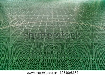 Green plastic tiles floor of basketball court with white line