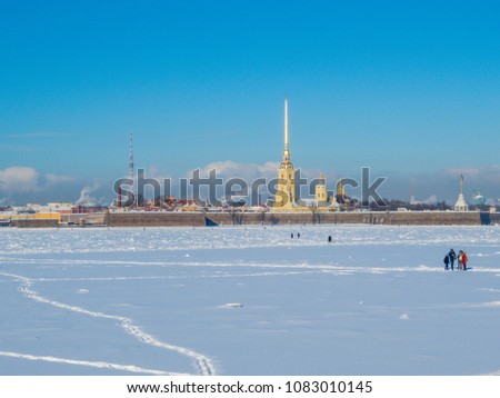 People walking on the frozen Neva River with the Peter and Paul Fortress in the background. In St. Petersburg, Russia 