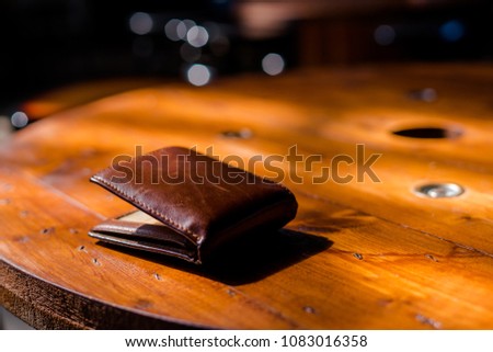 The vintage wallet on the wood table.Dramatic light. Royalty-Free Stock Photo #1083016358