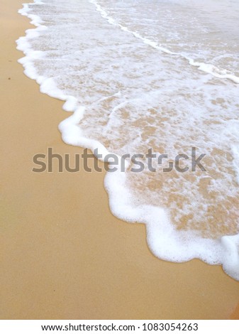 Sea waves on a sandy beach on a cloudy day with blurred background