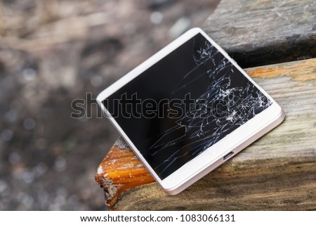 Smartphone with broken display screen is lying on the wooden bench. Selective focus