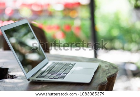 Wood table top with computer laptop on blurred the nature background.