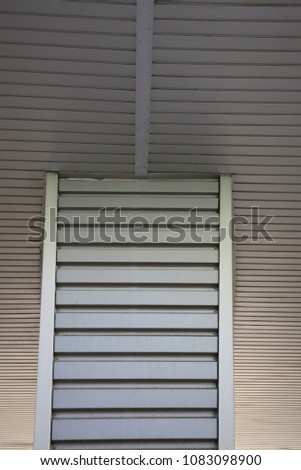Abstract view of part of metallic ceiling and pillar in a building hall. Pattern of grey alluminium stripped sheets. Vintage design with dark lines and angles. Architectural image.