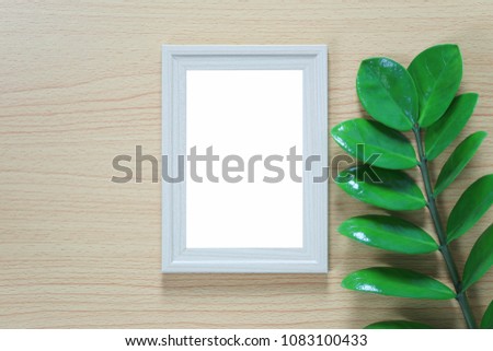 Vintage photo frame on a wooden floor and green leaf of branch put aside and have copy space to in put idea for design in your concept.