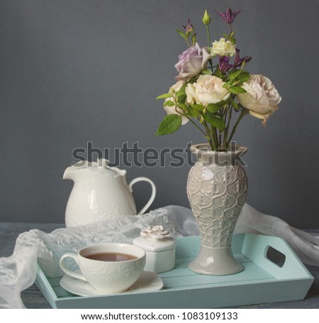  fresh white roses in vase with a cup of tea