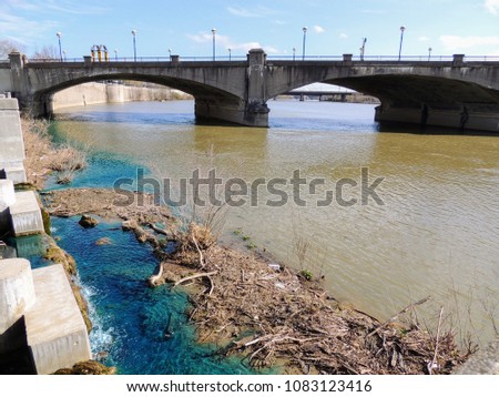 Pedestrian bridge in White River State Park Indianapolis Indiana with muddy and vivid blue water mixing