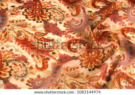 Texture, pattern, background. Silk fabric - paisley on a beige background. This beautiful silk border print has paisley and floral print in orange and grey on a natural colored background.