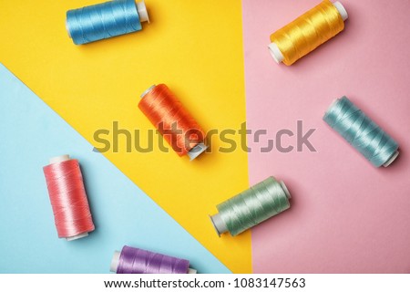 Flat lay composition with sewing threads on color background Royalty-Free Stock Photo #1083147563