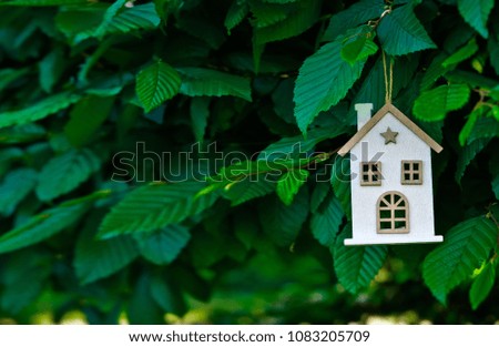 white wooden house on the background of a tree with green leaves, building advertising caring for a family in nature
