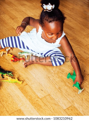 little cute african american girl playing with animal toys at ho