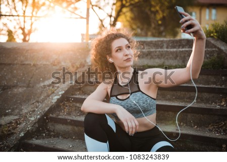 Young woman in sportswear is getting ready to start running with her favorite music on earphones