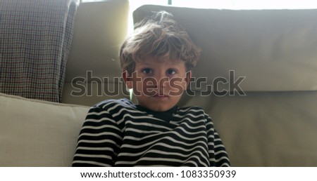 Child face watching television. Young boy seated in sofa