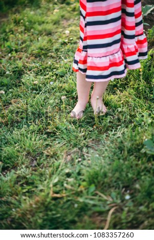 A beautiful little girl walks the garden barefoot. Blossoming spring and back light. Happiness in childhood