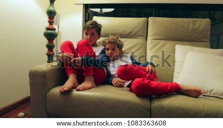 Boys seated on sofa watching TV off camera. candid authentic real life children watching screen at home