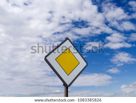 Traffic Signs / Germany: Priority road sign in front of a cloudy blue sky