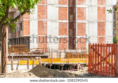 New residential building construction site entrance with gate of safety net fence with view on the concrete and metal reinforcement on the base 