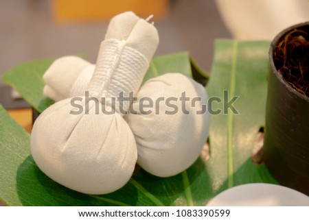 Herbal compress ball on plastic realistic leaf on wood table, Thai massage, Spa theme concept Royalty-Free Stock Photo #1083390599