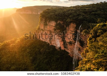 Stunning sunset over high waterfall falling from the cliffs in Chapada dos Guimaraes national park,Brazil Royalty-Free Stock Photo #1083402938