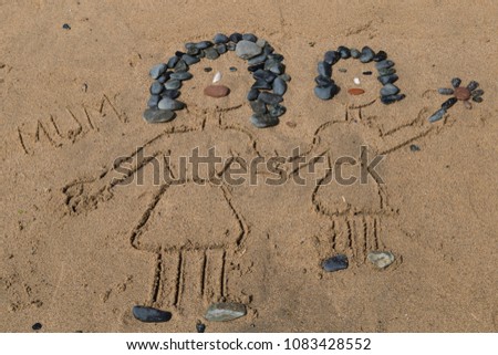 drawing a picture with stones of mother's day on sand on the beach.