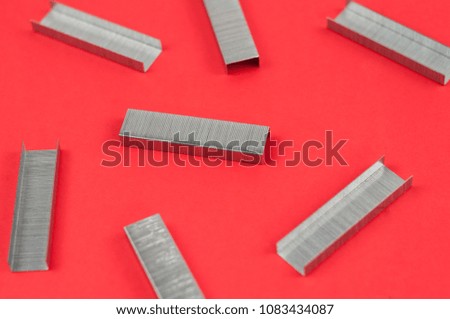Scattered stationery new metal clips for stapler on red background