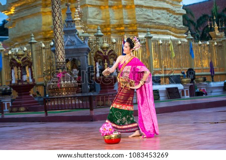 portrait of a young beautiful Thai dancer dancing in front of the pagoda of Wat Prathat Hariphunchai, Lampoon, Thailand