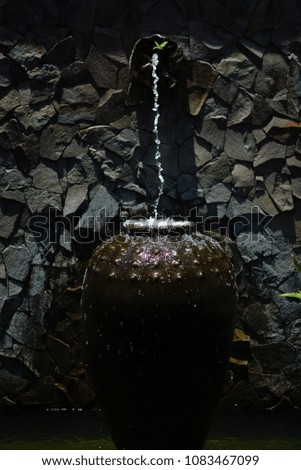 water fountain pouring into clay vase.