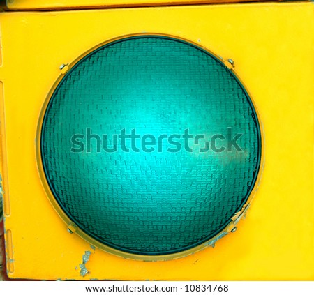 Extra large green light glows in casing of yellow rustic metal.