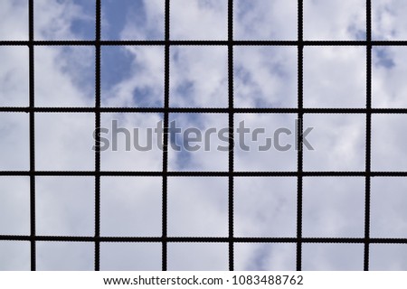 metal prison lattice, on a background, blue sky with white clouds, bottom view