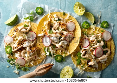 Delicious tacos with grilled fish, cilantro, lime, cabbage, carrot, jalapeno and radish with mexican chili crema sauce.