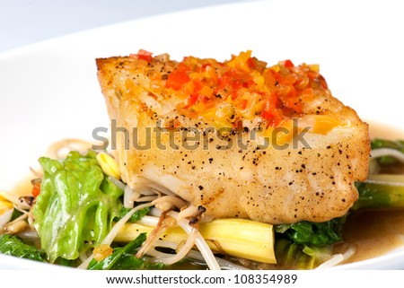 Baked halibut with vegetable garnish on a white plate